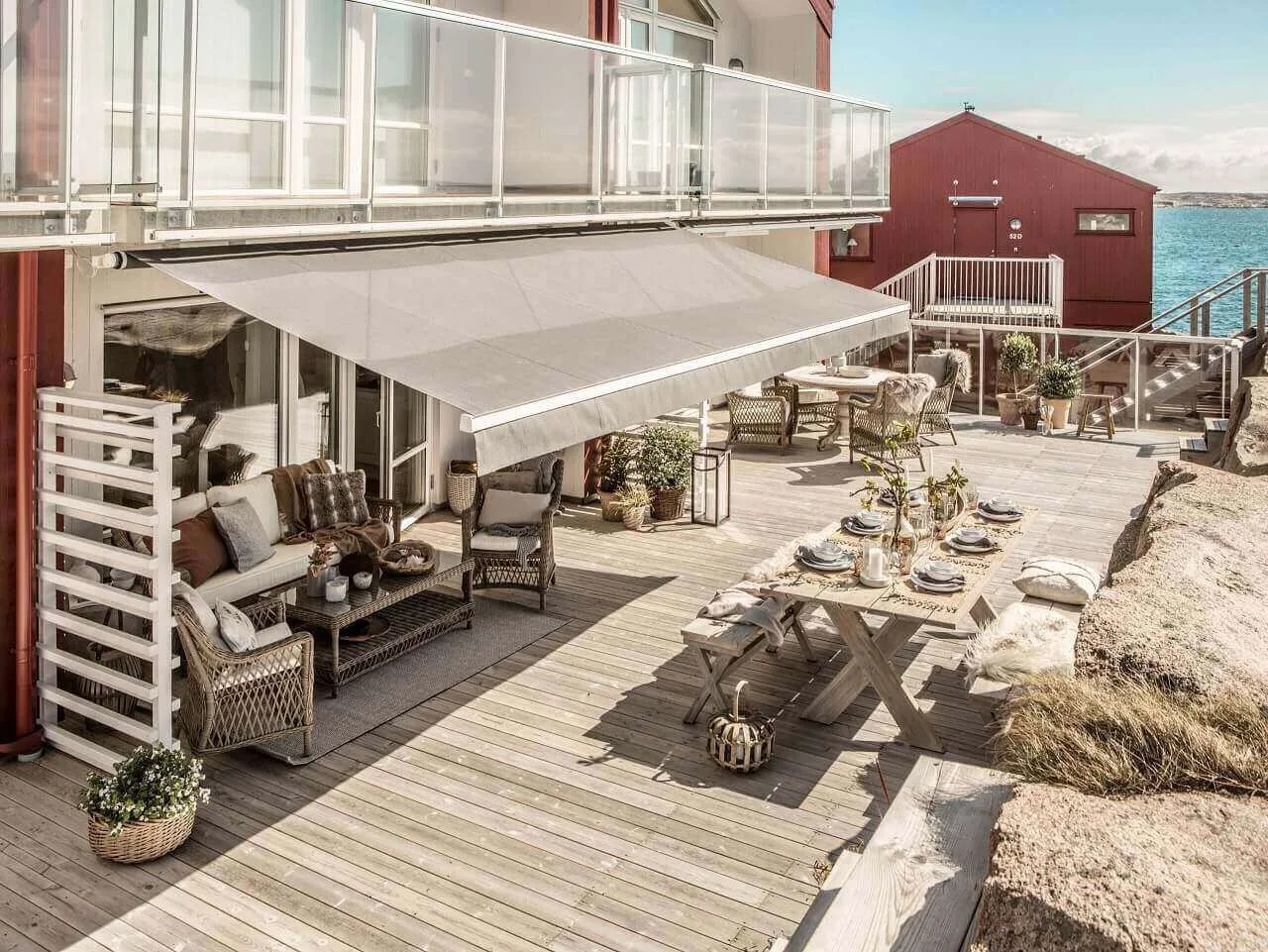 Terrass vid havet med utemöbler i skuggan av en stor markis